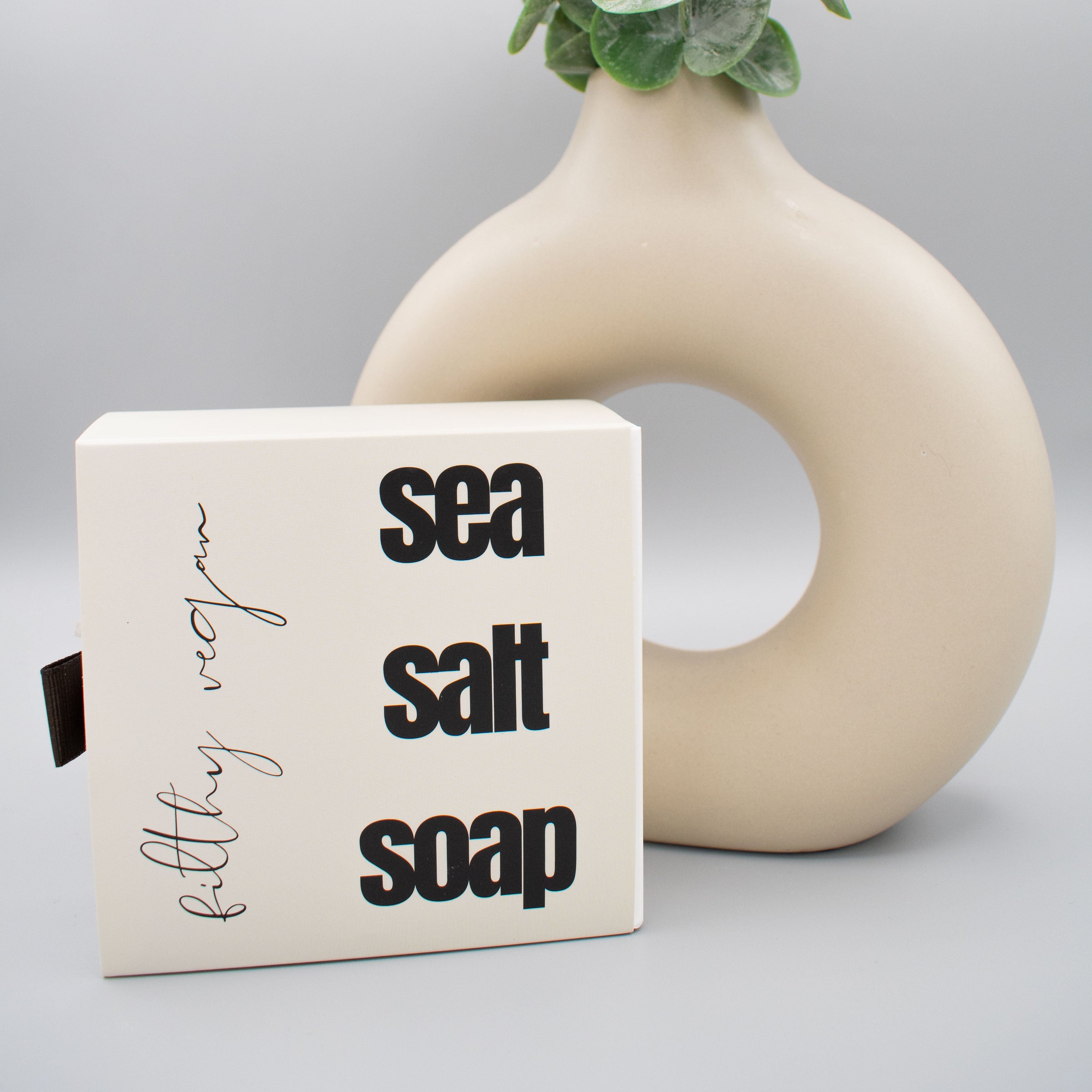 Sea salt soap bar with a decorative vase and greenery on a light background