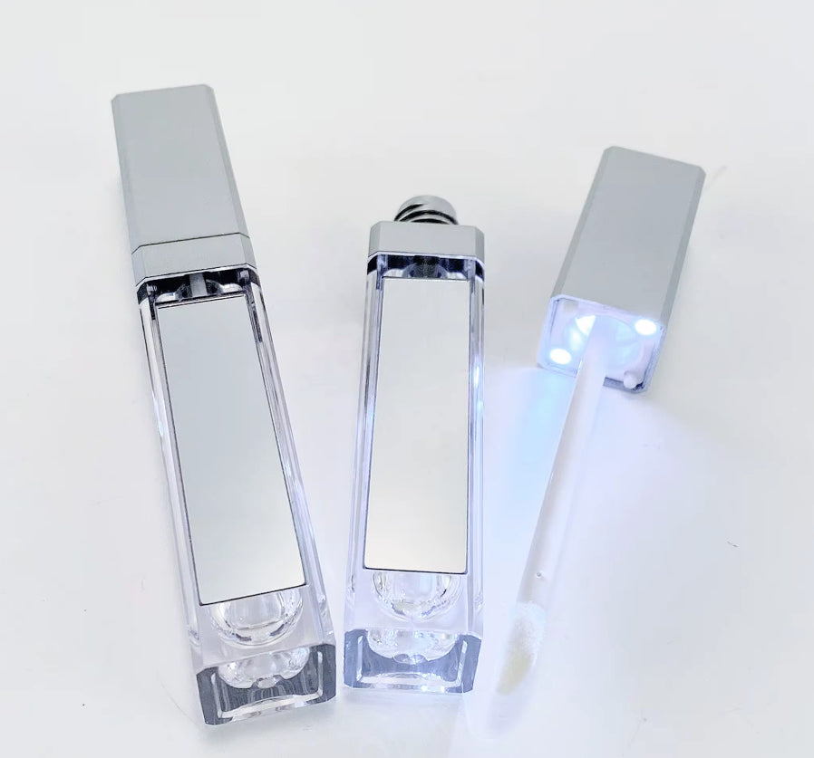 Three clear cosmetic bottles with silver caps on a white background